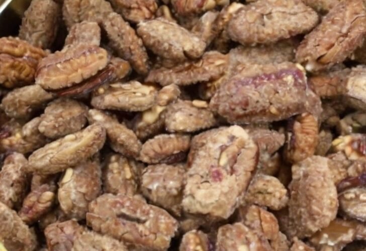 A round decorative tin filled with homemade candied pecan halves coated in a crunchy cinnamon-sugar mixture.