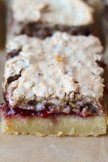 A close-up of raspberry crumble bars with a buttery golden shortbread base, a rich layer of raspberry filling, and a crumbly, lightly browned topping.