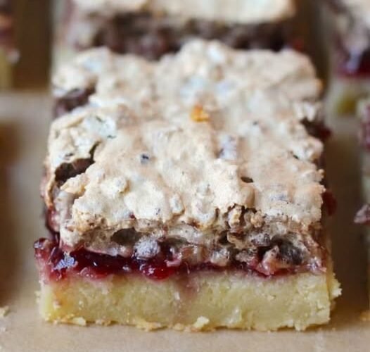 A close-up of raspberry crumble bars with a buttery golden shortbread base, a rich layer of raspberry filling, and a crumbly, lightly browned topping.