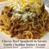 A hearty plate of cheesy beef spaghetti coated in a rich, creamy garlic-cheddar sauce, topped with seasoned ground beef and a generous layer of melted cheese