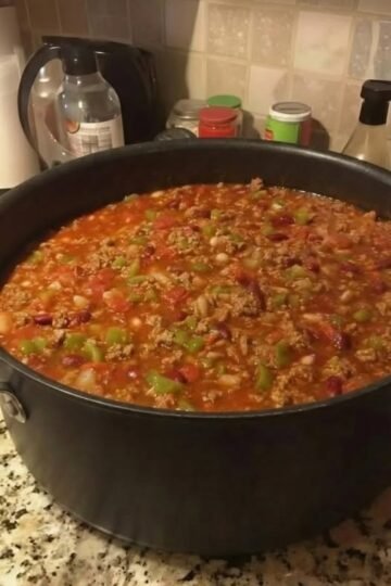 A hearty pot of homemade beef chili loaded with ground beef, beans, tomatoes, onions, and colorful green peppers in a rich, savory tomato-based sauce.