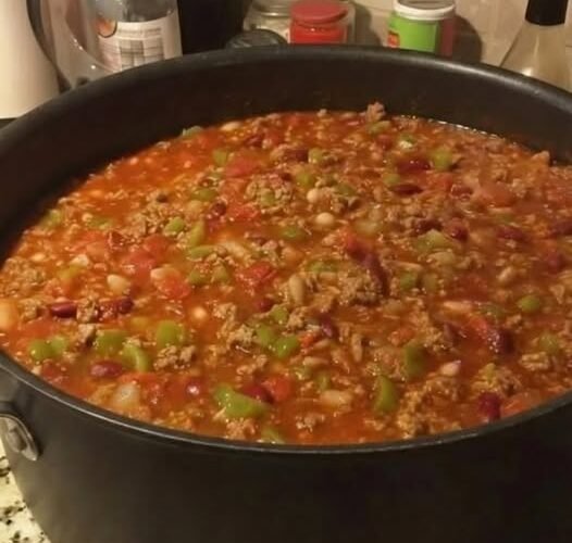 A hearty pot of homemade beef chili loaded with ground beef, beans, tomatoes, onions, and colorful green peppers in a rich, savory tomato-based sauce.