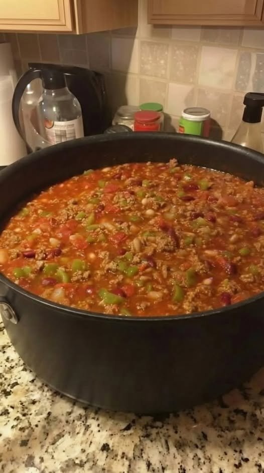 A hearty pot of homemade beef chili loaded with ground beef, beans, tomatoes, onions, and colorful green peppers in a rich, savory tomato-based sauce.