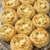 Golden-brown savory pinwheels filled with creamy cheese and chopped green pickles, baked until crisp around the edges and lightly browned on top.