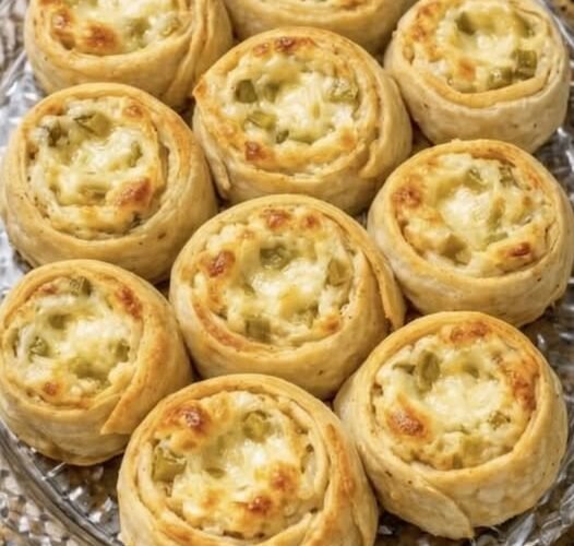 Golden-brown savory pinwheels filled with creamy cheese and chopped green pickles, baked until crisp around the edges and lightly browned on top.