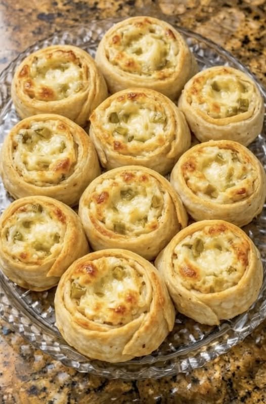 Golden-brown savory pinwheels filled with creamy cheese and chopped green pickles, baked until crisp around the edges and lightly browned on top.