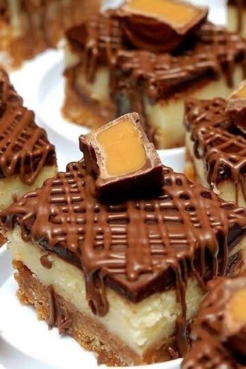 Decadent Rolo cheesecake bars with a buttery graham cracker crust, creamy cheesecake center, rich chocolate topping, and Rolo candies with gooey caramel centers on top.
