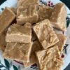 A plate of chunky, golden-brown peanut butter fudge squares with a rich, creamy texture and slightly crumbly edges.
