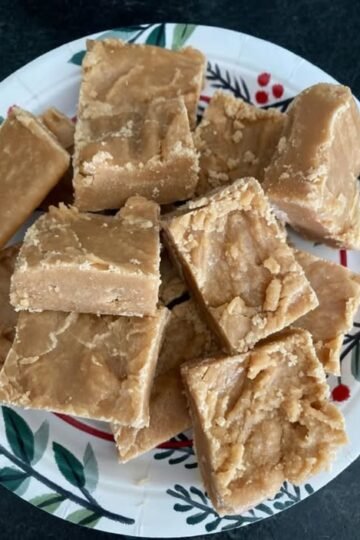 A plate of chunky, golden-brown peanut butter fudge squares with a rich, creamy texture and slightly crumbly edges.