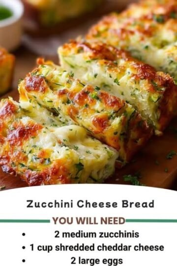 A golden, cheesy zucchini bread loaf with a crisp browned crust, tender zucchini-filled center, melted cheese throughout, and fresh herbs sprinkled on top.