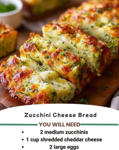 A golden, cheesy zucchini bread loaf with a crisp browned crust, tender zucchini-filled center, melted cheese throughout, and fresh herbs sprinkled on top.