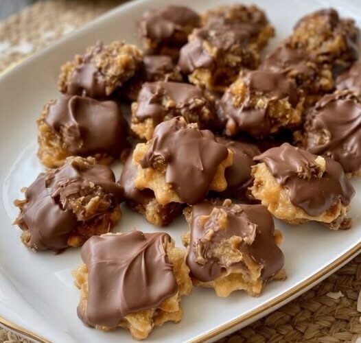 A plate of golden, chewy pecan cookies topped with rich melted chocolate, featuring crunchy chopped pecans and a soft, buttery center.