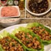Tender seasoned ground chicken served in crisp lettuce cups, coated in a savory Asian-inspired sauce and garnished with green onions and sesame seeds.