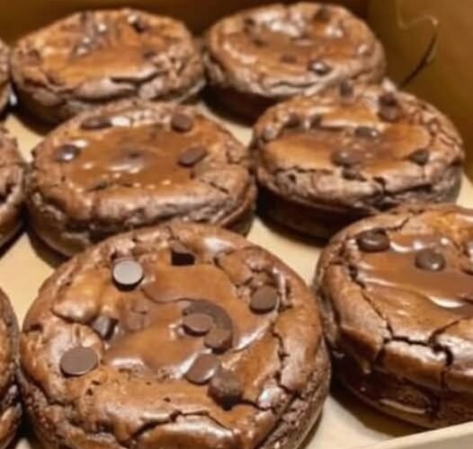 A box of thick, fudgy chocolate brownie cookies topped with plenty of semi-sweet chocolate chips, featuring crackly tops and rich, gooey centers