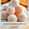A stack of soft orange creamsicle truffles coated in powdered sugar, with a delicate citrus-orange center and fresh orange slices blurred in the background.