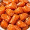 A bowl of tender baby carrots coated in a glossy, buttery-sweet glaze, seasoned with black pepper and caramelized until beautifully shiny.