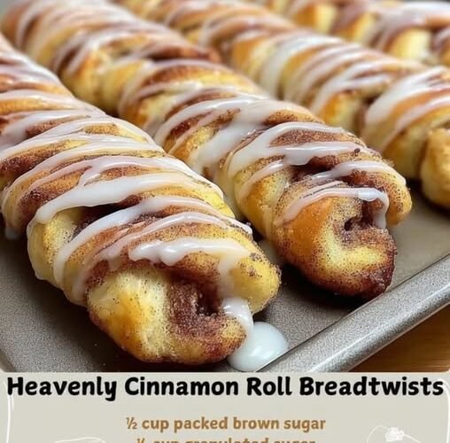 Golden-brown cinnamon roll bread twists arranged on a baking sheet, filled with cinnamon-sugar swirls and finished with a generous drizzle of white vanilla glaze.