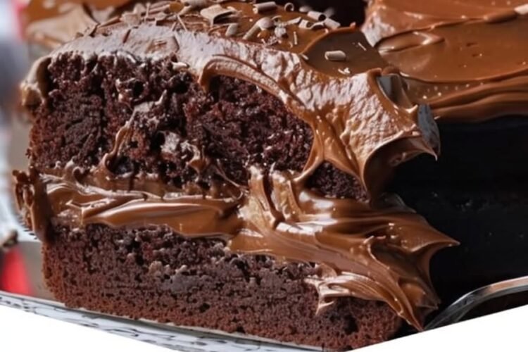 A rich double chocolate Coca-Cola cake with a moist, fudgy chocolate crumb, covered in glossy chocolate frosting and topped with delicate chocolate shavings.