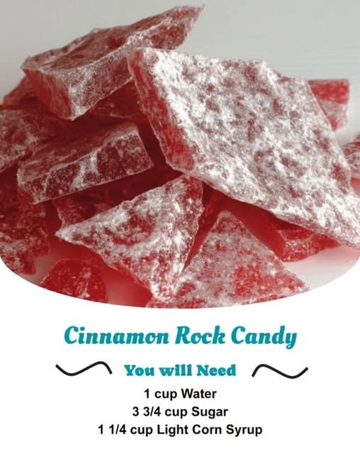 A pile of glossy red cinnamon rock candy pieces dusted generously with powdered sugar, with a crisp, glass-like texture and a sweet, spicy cinnamon flavor