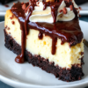 Fudgy brownie base, a silky vanilla cheesecake middle, and glossy hot fudge poured on at the last second. One 9-inch springform pan, twelve generous slices, and roughly four hours of mostly waiting.