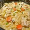 Creamy chicken pot pie noodle skillet filled with tender chicken, egg noodles, bright carrots and green peas in a rich, savory cream sauce, garnished with fresh herbs and black pepper.
