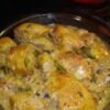 Golden-browned chicken legs smothered in a rich creamy mushroom sauce with sliced mushrooms, garlic, and herbs, served hot in a glass baking dish.