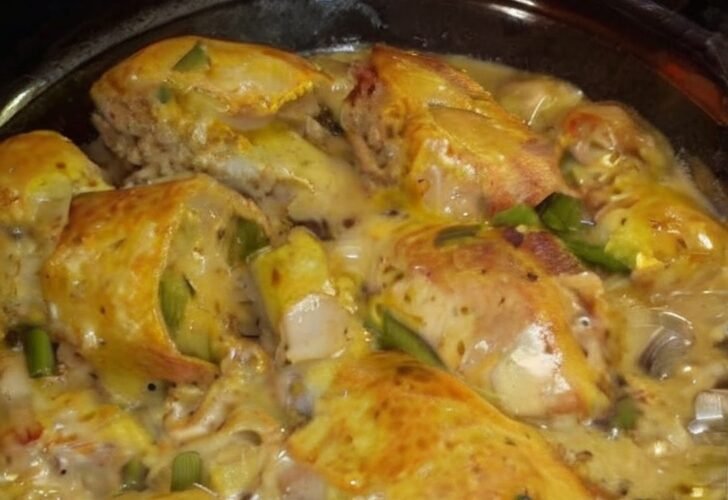 Golden-browned chicken legs smothered in a rich creamy mushroom sauce with sliced mushrooms, garlic, and herbs, served hot in a glass baking dish.