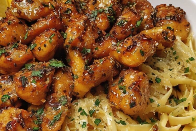 Juicy garlic-butter shrimp served over creamy pasta, glazed with a rich golden sauce, garnished with fresh parsley and lemon wedges.