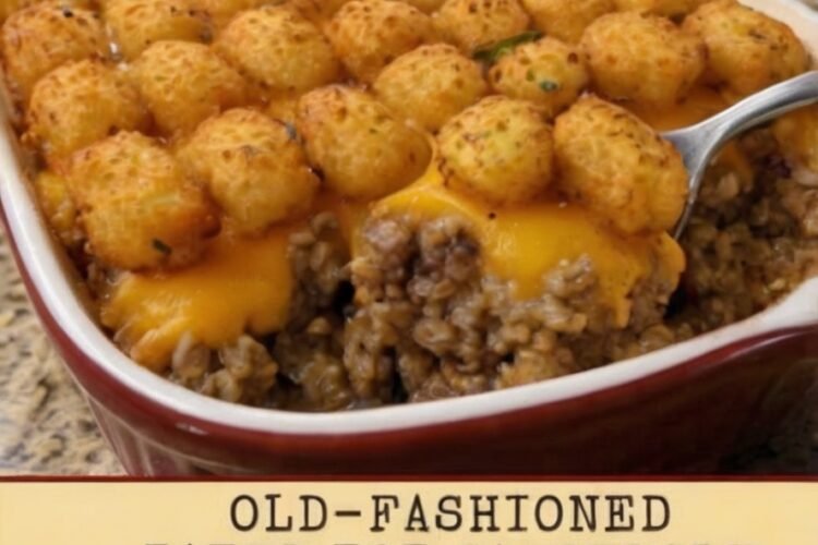 A hearty old-fashioned tater tot casserole in a red-and-white baking dish, topped with crispy golden tater tots and melted cheddar cheese over a creamy seasoned ground beef and onion filling.