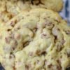 A stack of thick, soft-baked toffee pecan cookies with lightly golden edges, crumbly centers, and generous pieces of buttery toffee and chopped pecans throughout.