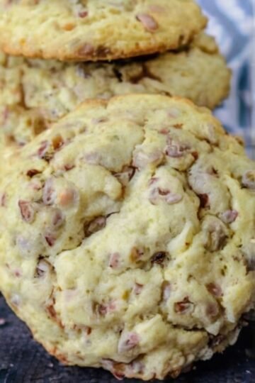 A stack of thick, soft-baked toffee pecan cookies with lightly golden edges, crumbly centers, and generous pieces of buttery toffee and chopped pecans throughout.
