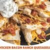 A stack of golden, crispy chicken bacon ranch quesadillas filled with tender chicken, melted cheddar cheese, and crispy bacon, served with a dollop of sour cream for dipping.