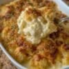 Creamy cheesy chicken casserole topped with a golden, crispy layer of crushed buttery crackers and fresh herbs, served hot in a white baking dish.