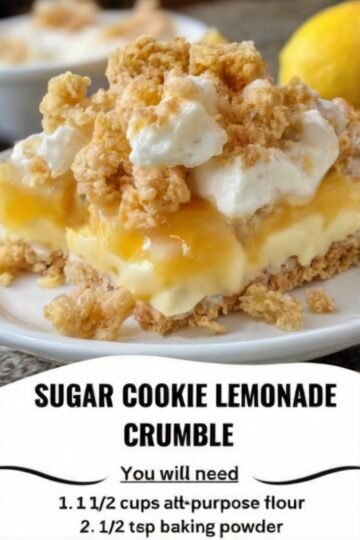 A slice of sugar cookie lemonade crumble topped with creamy lemon filling, whipped cream, and golden buttery cookie crumbs, with a bright lemon in the background.
