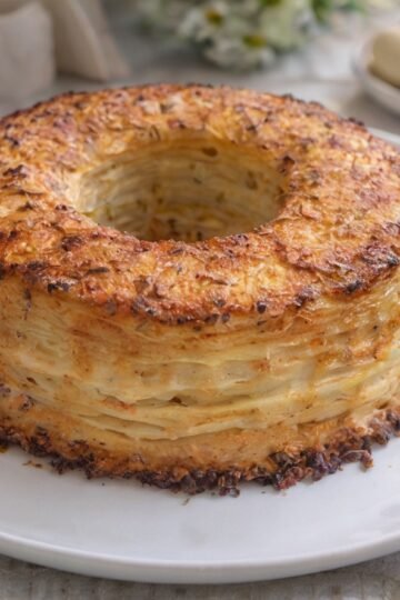 A beautifully golden layered potato ring with crisp, browned edges and delicate layers of tender potatoes throughout, baked into an elegant wreath shape.