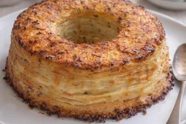 A beautifully golden layered potato ring with crisp, browned edges and delicate layers of tender potatoes throughout, baked into an elegant wreath shape.