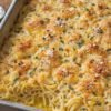 A creamy baked spaghetti casserole in a rectangular baking dish, topped with a golden-brown crispy Parmesan breadcrumb crust and sprinkled with fresh parsley.
