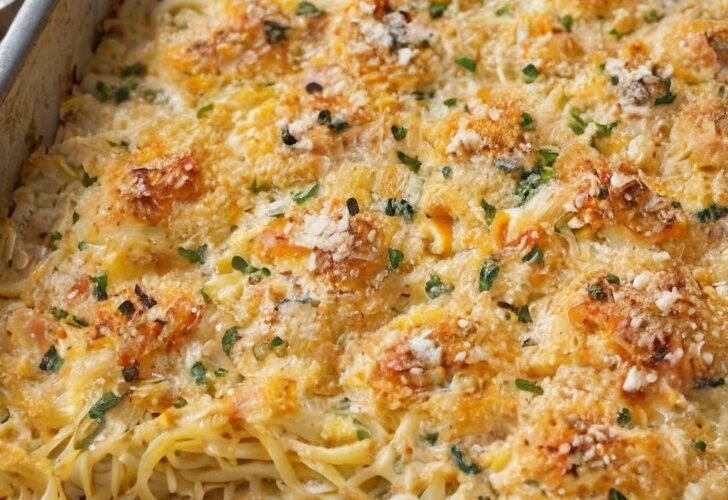 A creamy baked spaghetti casserole in a rectangular baking dish, topped with a golden-brown crispy Parmesan breadcrumb crust and sprinkled with fresh parsley.
