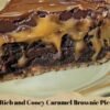 A rich caramel brownie pie slice with a buttery crust, fudgy chocolate brownie filling, gooey caramel layers, and a glossy chocolate topping.