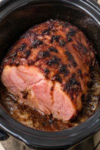 Four golden-brown pork chops topped with melting butter and herbs, each wrapped in crinkled aluminum foil inside a white slow cooker, with savory juices pooling around the tender, juicy meat.