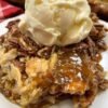 A decadent pecan pie cobbler topped with toasted pecans, gooey caramel-like filling, flaky pastry, and a generous scoop of vanilla ice cream melting over the warm dessert. leitesculinaria.com