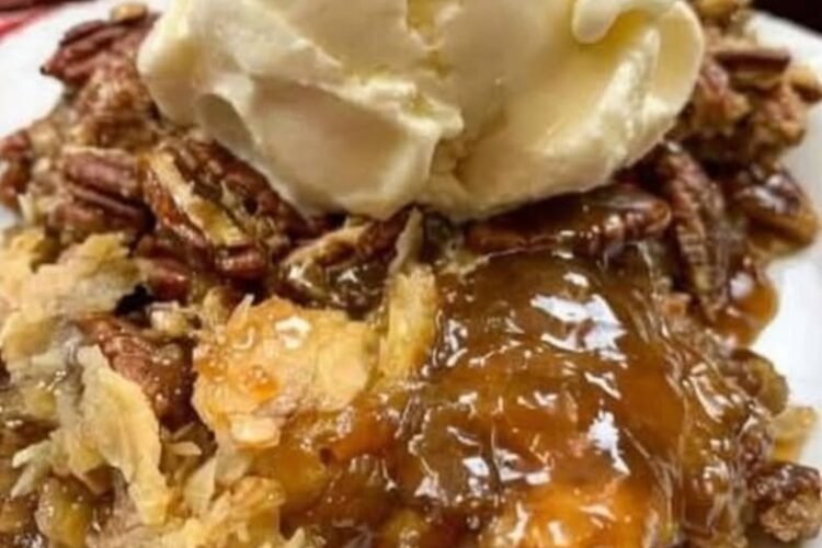 A decadent pecan pie cobbler topped with toasted pecans, gooey caramel-like filling, flaky pastry, and a generous scoop of vanilla ice cream melting over the warm dessert. leitesculinaria.com