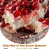 A luscious Cherries in the Snow dessert with a fluffy white cream cheese layer, tender cake base, and glossy ruby-red cherries piled generously on top.