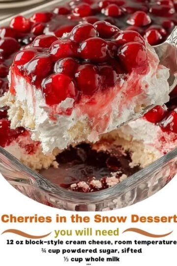 A luscious Cherries in the Snow dessert with a fluffy white cream cheese layer, tender cake base, and glossy ruby-red cherries piled generously on top.