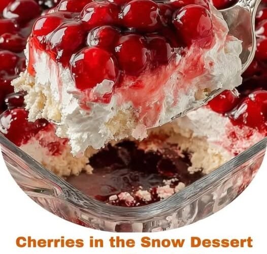 A luscious Cherries in the Snow dessert with a fluffy white cream cheese layer, tender cake base, and glossy ruby-red cherries piled generously on top.