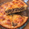 A pound of browned beef and onion under a biscuit-mix batter that sets into its own crust, finished with cheddar browned on top. One skillet, one pie plate, one oven, forty minutes.