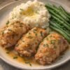 Golden-brown stuffed chicken breasts served with creamy mashed potatoes and tender green beans, all drizzled with a savory pan sauce and finished with fresh chopped herbs.