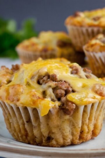 Golden-brown savory cheeseburger muffins packed with seasoned ground beef and topped with gooey melted cheddar, with a tender, flavorful muffin base and crispy edges. muffinmama.com