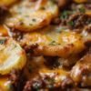A comforting cheesy ground beef and potato casserole with tender golden potato slices, savory seasoned beef, and melted cheddar cheese, baked until bubbly and garnished with fresh herbs