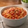 A comforting bowl of elbow macaroni tossed in a rich, chunky tomato sauce, topped with cracked black pepper and served piping hot for a simple, hearty homemade meal.